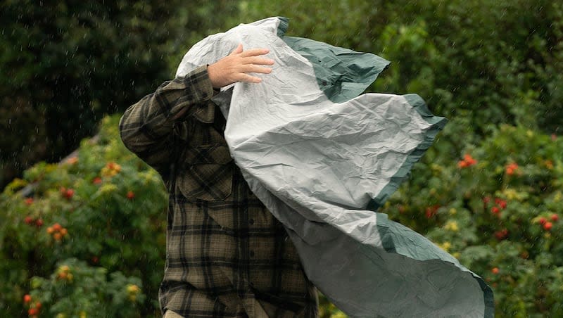 A tourist struggles with his rain poncho in strong wind as weather associated with Storm Lee hits the region, Saturday, Sept. 16, 2023, in Bar Harbor, Maine. States across the southern and eastern U.S. are under severe weather alerts including thunderstorms, high winds and possible tornadoes.