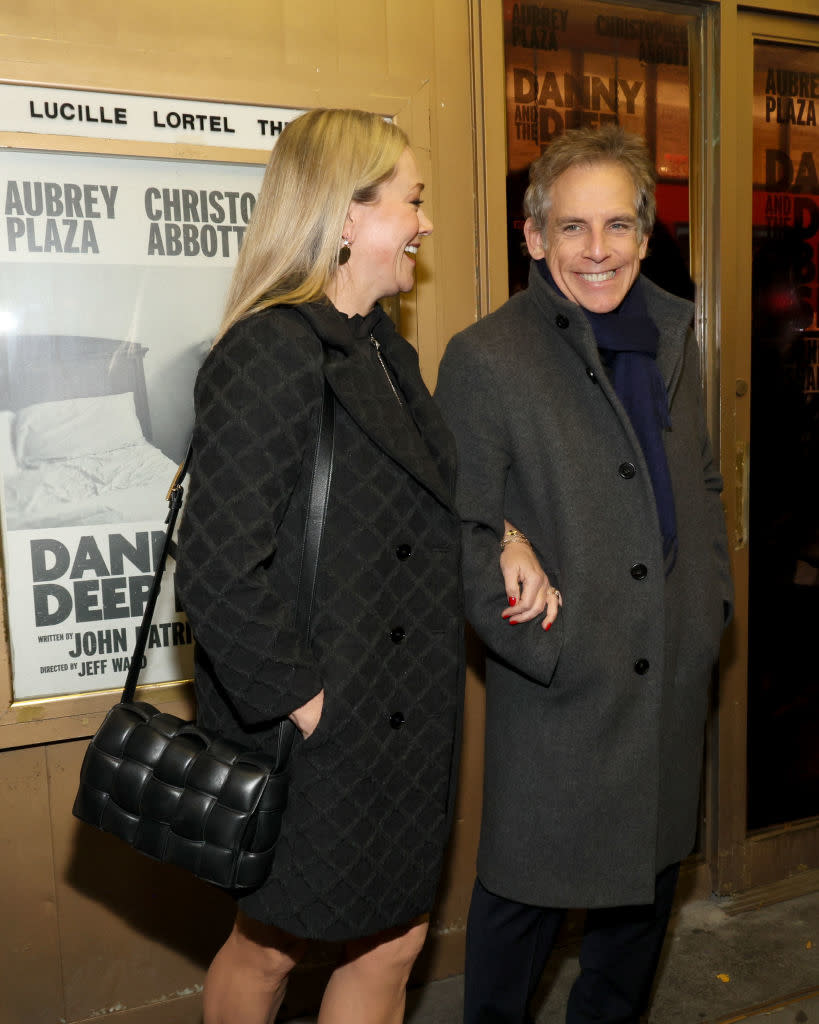 the couple smiling outside a theatre, Christine with quilted coat and purse, Ben in a long coat