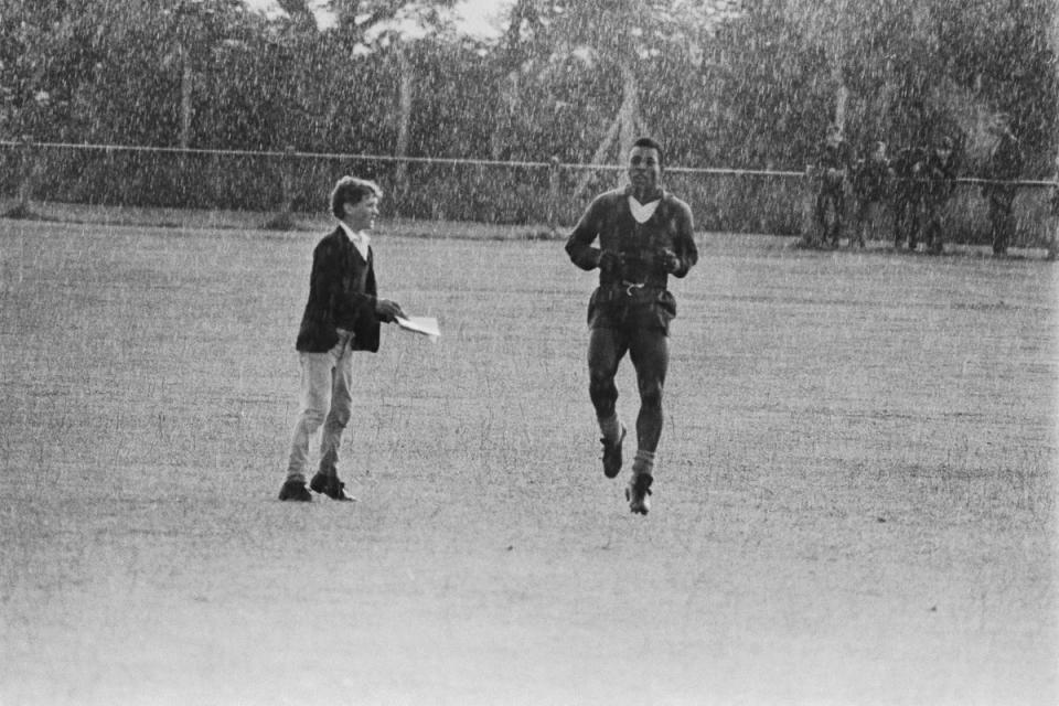 A young fan approaches Pele for an autograph while he is training in the pouring rain in Bolton in preparation for Brazils match against Portugal, 18th July 1966. (Getty Images)