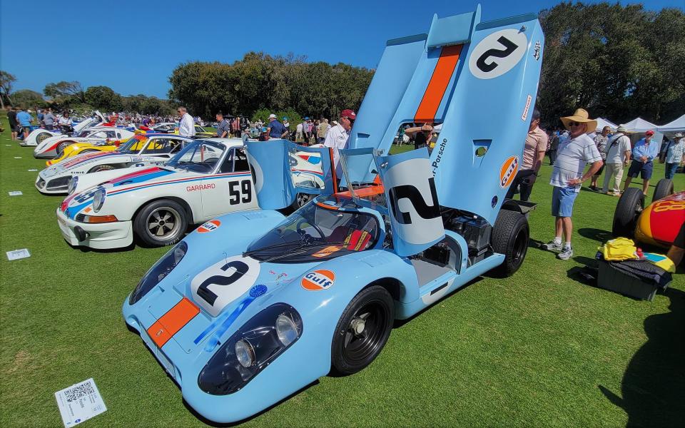 A blue 1969 Porsche 917K with rear deck up entices viewers to look at its engine, parked in a line of race cars honoring the 60th anniversary of the 24 Hours of Daytona.