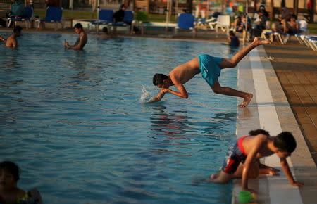 A Palestinian jumps into a swimming pool as he enjoys the warm weather with his family at the Blue Beach Resort in Gaza July 30, 2015. REUTERS/Mohammed Salem