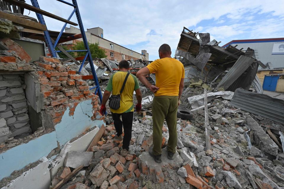 Two men walk among debris of destroyed warehouse and workshops as a result of missile strike in Kharkiv (AFP via Getty Images)