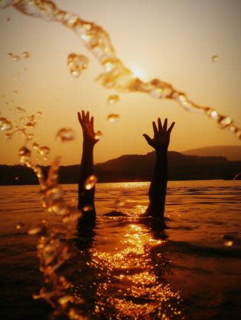 Two hands raising out of a body of water