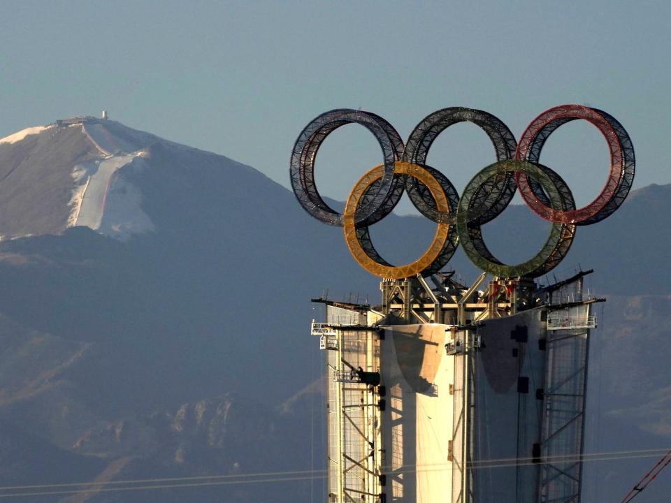 The Olympic rings sit atop a tower with mountains in the background near Beijing.