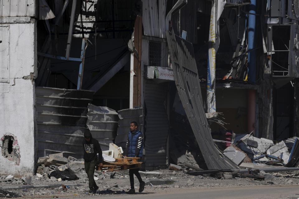 Palestinians salvage materials from a factory destroyed in the Israeli bombardment of the Gaza Strip in Deir al Balah, Gaza Strip, Thursday, Feb. 15, 2024. (AP Photo/Adel Hana)