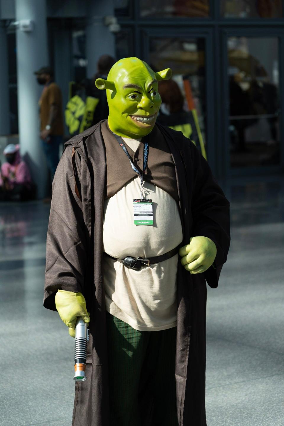 A cosplayer dressed as Shrek with a lightsaber at New York Comic Con 2021.