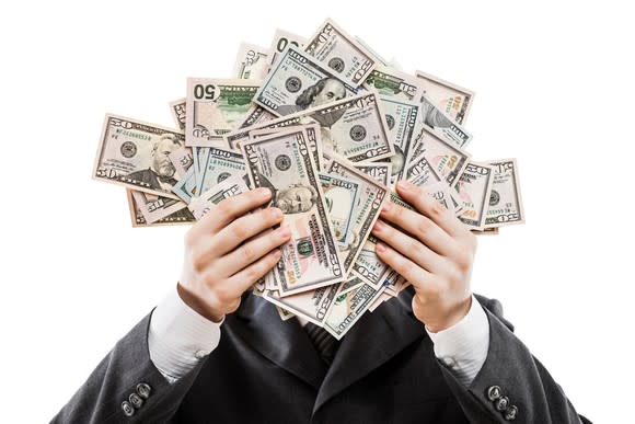 Businessman holding a lot of cash in his hands that cover his face