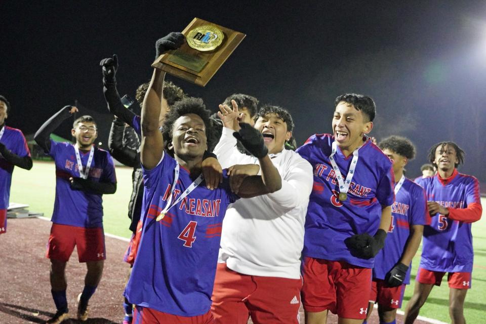 Mount Pleasant senior Moises Augustin shows off the Division IV championship plaque to family and friends in the stands at Rhode Island College following Sunday's drama-filled 1-0 win over Woonsocket on Sunday night.