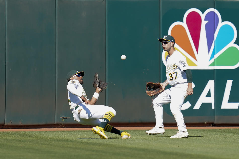 Oakland Athletics left fielder Tony Kemp, left, catches a fly ball hit by Seattle Mariners' Jesse Winker during the ninth inning of a baseball game in Oakland, Calif., Sunday, Aug. 21, 2022. (AP Photo/Godofredo A. Vásquez)