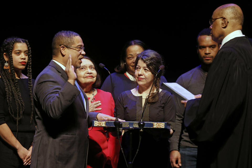 FILE - In this Monday, Jan. 7, 2019, file photo, former U.S. Rep. Keith Ellison, second from left, surrounded by family members, places his hand on the Koran as U.S. District Judge Michael Davis administers the oath of office for the new Minnesota attorney general during ceremonies in St. Paul, Minn. Taking over as lead prosecutor in George Floyd's death is giving Ellison a national platform to talk about race in America. And while Ellison is careful not to talk about details of the criminal cases against four Minneapolis police officers, he's grabbing the opportunity to raise issues about police reform that he's worked on in the past. (AP Photo/Jim Mone, File)