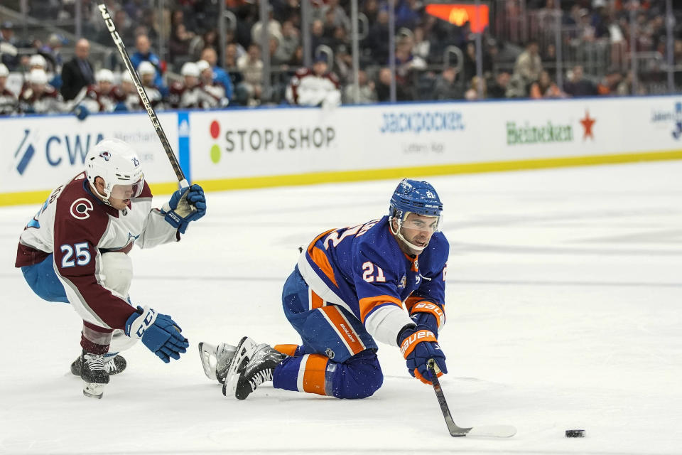 Colorado Avalanche right wing Logan O'Connor (25) and New York Islanders centerman Kyle Palmieri (21) battle for the puck in the second period of an NHL hockey game, Saturday, Oct. 29, 2022, in Elmont, N.Y. (AP Photo/Eduardo Munoz Alvarez)