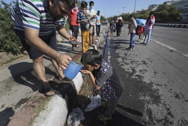 A resident offers water to a child of a migrant daily wage labourer as he and his family make the journey to their village following a lockdown amid concern over the spread of coronavirus in New Delhi, India