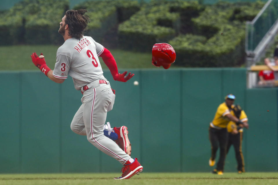 Philadelphia Phillies' Bryce Harper (3) loses his helmet as he digs for second base while Pittsburgh Pirates center fielder Starling Marte, center, throws the ball to second in in the first inning of a baseball game, Sunday, July 21, 2019, in Pittsburgh. Harper was safe with a double. (AP Photo/Keith Srakocic)