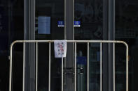 FILE - A COVID controls closure notice is placed on a barricade in front of a shuttered restaurant at a commercial office building in Beijing, Nov. 23, 2022. (AP Photo/Andy Wong, File)