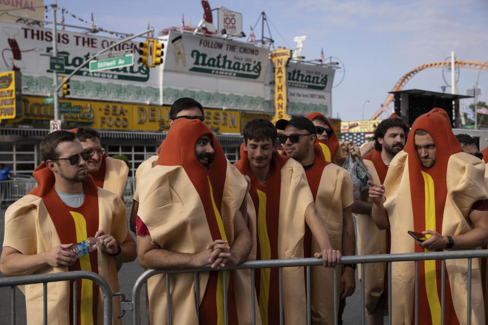 Personas disfrazadas de "hot dogs" se reúnen antes de que comience el famoso concurso de comer perros calientes organizado por Nathan's, el martes 4 de julio de 2023, en Coney Island, Nueva York. (AP Foto/Yuki Iwamura)