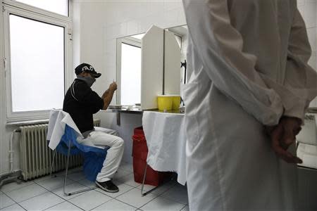 A paramedic watches a drug user as he prepares himself for an injection with a narcotic drug inside a supervised injection hall in Athens November 25, 2013. REUTERS/Yorgos Karahalis
