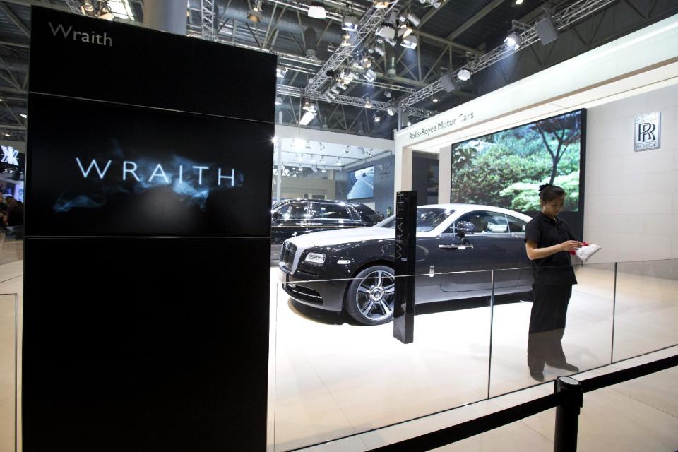 A cleaner folds a cloth wipe near a Rolls-Royce Wraith displayed at the China Auto show in Beijing, Wednesday, April 23, 2014. Luxury automakers, like their mass-market counterparts, are looking to China to drive future growth and are investing heavily to gain or expand a foothold in its market. (AP Photo/Alexander F. Yuan)