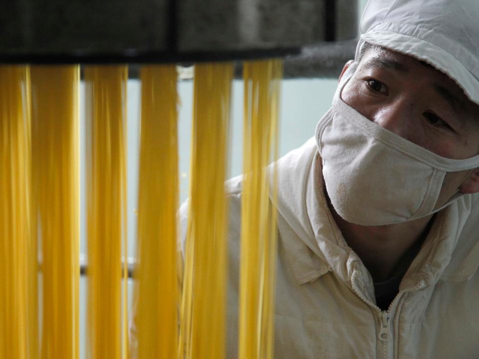 An employee of the Pyongyang Corn Processing Factory watches corn noodles being made Thursday, Dec. 10, 2020, in Pyongyang, North Korea.