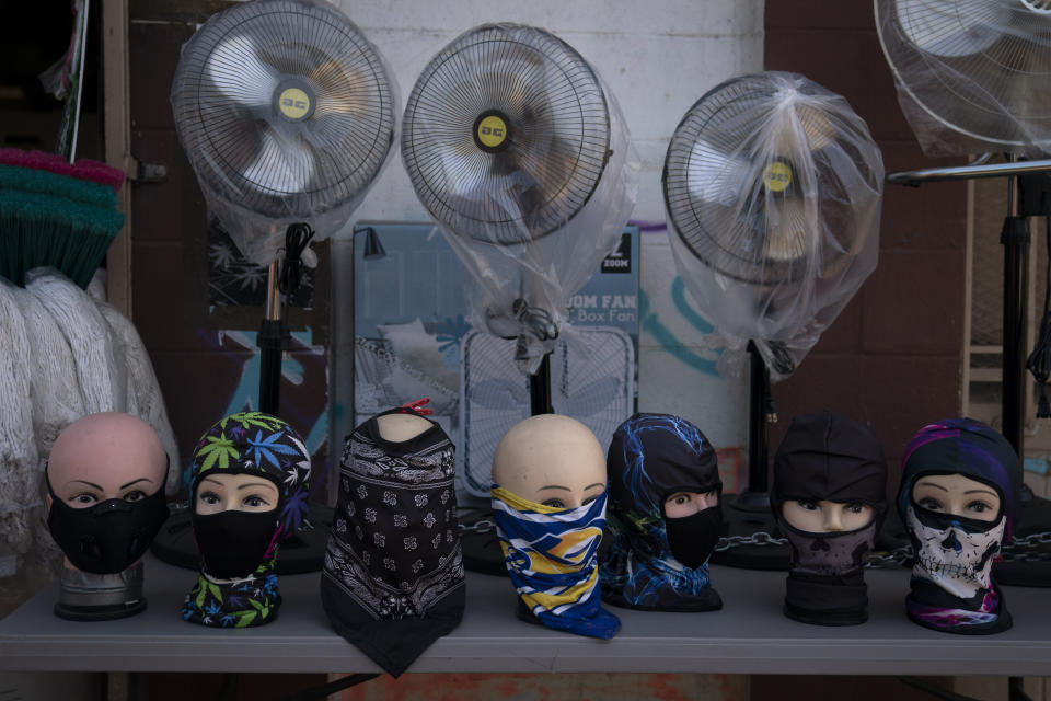 Mannequin heads donning face coverings are displayed along with fans for sale in front of a store Thursday, Oct. 1, 2020, in South Central Los Angeles. California's plan to safely reopen its economy will begin to require counties to bring down coronavirus infection rates in disadvantaged communities that have been harder hit by the pandemic. The complex new rules set in place an "equity metric" that will force larger counties to control the spread of the virus in areas where Black, Latino and Pacific Islander groups have suffered a disproportionate share of the cases due to a variety of socioeconomic factors. (AP Photo/Jae C. Hong)