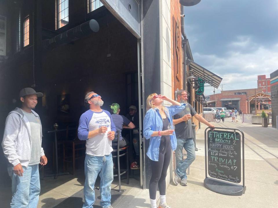 Haily Sloan (center) stands outside Ethereal Brewery in Lexington, Ky. to watch the solar eclipse April 8, 2024. Taylor Six