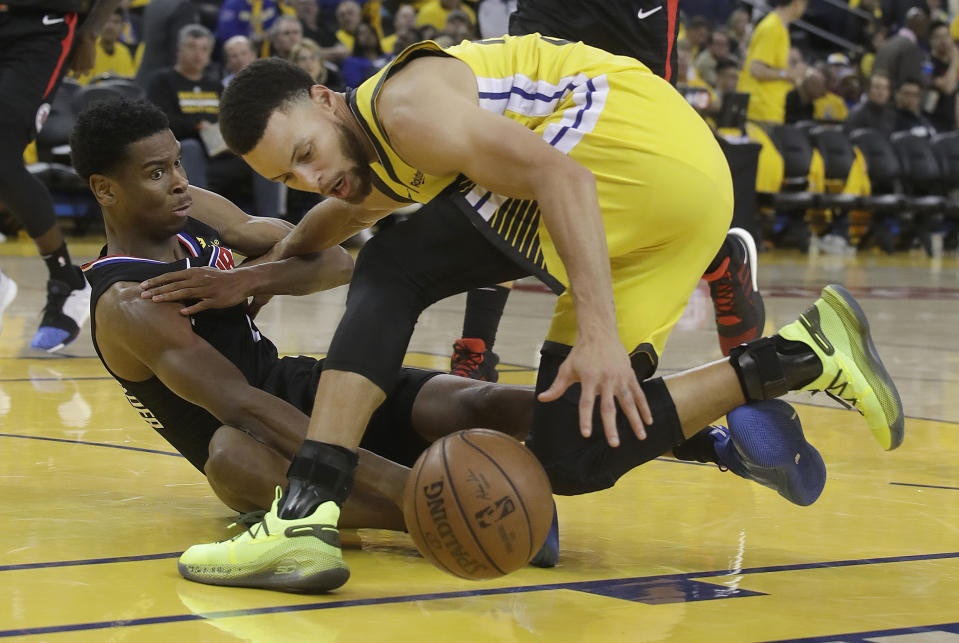 Los Angeles Clippers guard Shai Gilgeous-Alexander, left, and Golden State Warriors guard Stephen Curry reach for the ball during the second half of Game 2 of a first-round NBA basketball playoff series in Oakland, Calif., Monday, April 15, 2019. (AP Photo/Jeff Chiu)