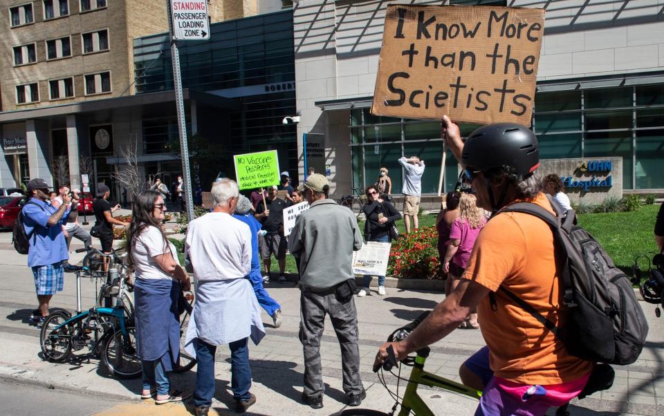 Healthcare workers staged a counter protest. One held a sign saying "I know more than the scientists" - Chris Young/The Canadian Press via AP