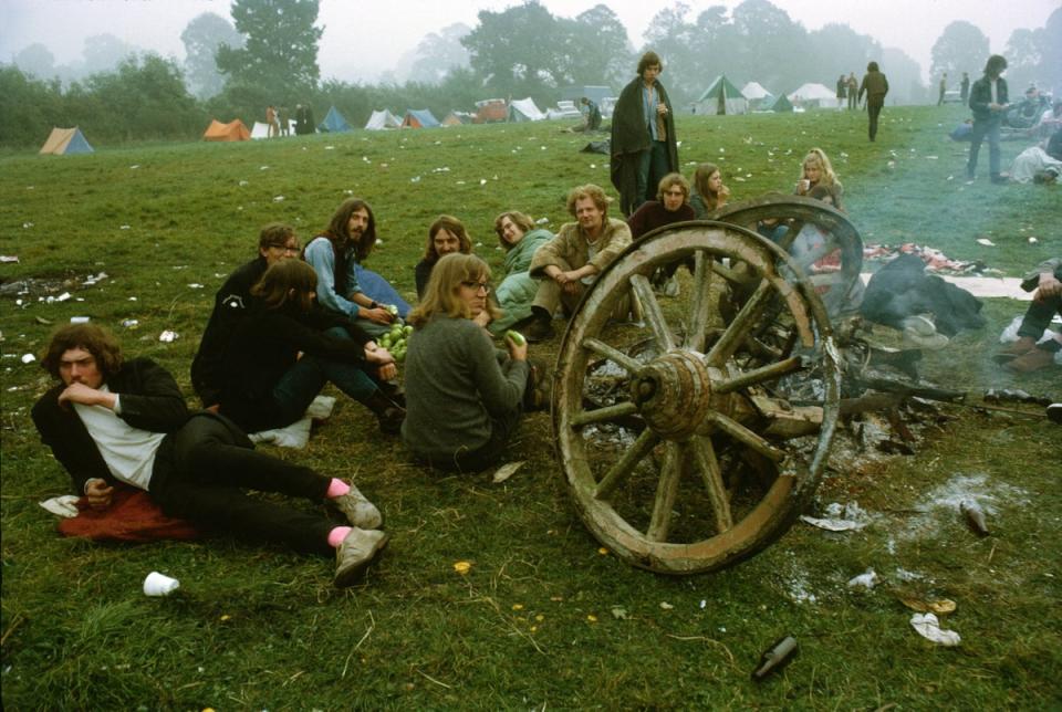 A group eating apples next to a smouldering wooden cart at the first Glastonbury Festival, 1970 (Getty Images)