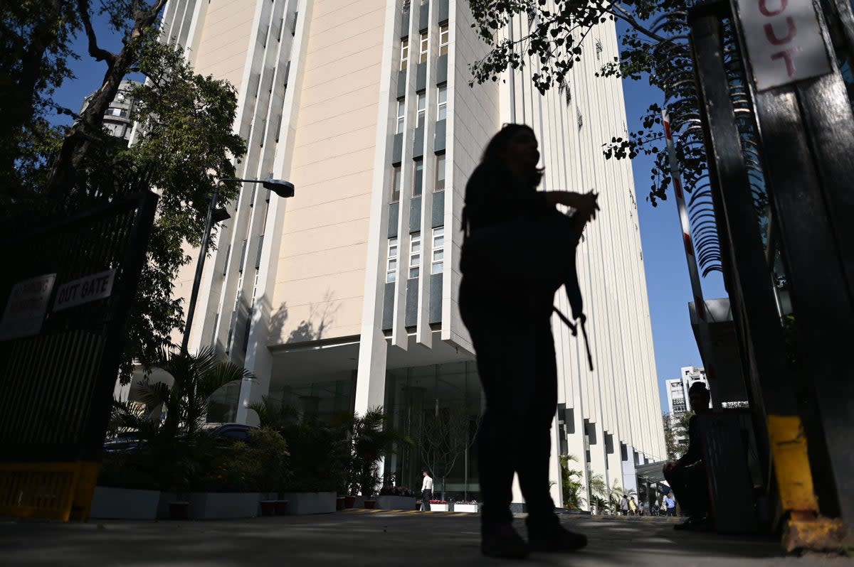 A woman stands at the entrance of the office building where Indian tax authorities raided BBC’s office in New Delhi (Getty)