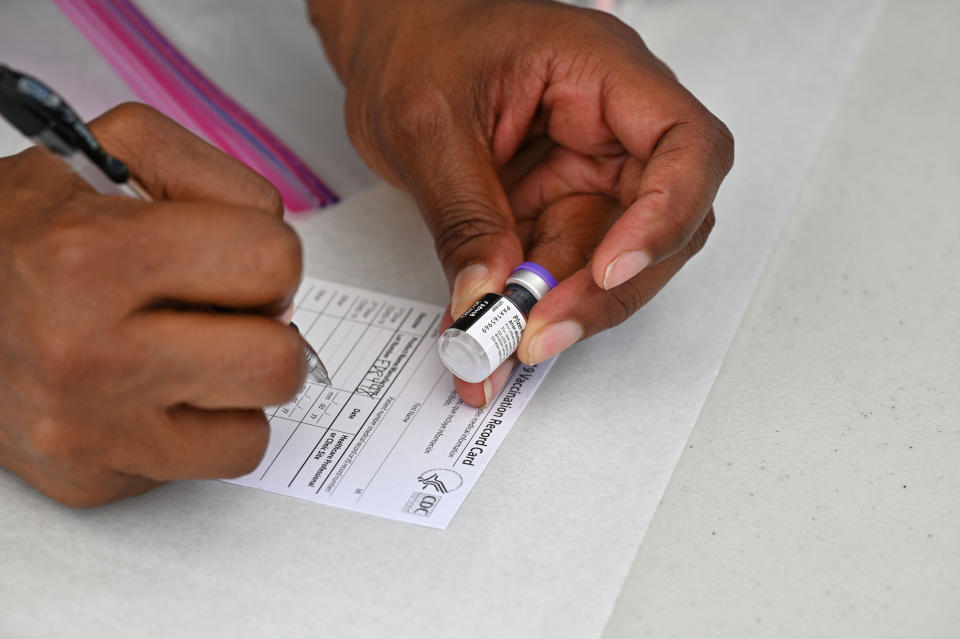 TOPSHOT - A healthcare worker fills out a Covid-19 vaccination card at a community healthcare event in a predominately Latino  neighborhood in Los Angeles, California, August 11, 2021. - All teachers in California will have to be vaccinated against Covid-19 or submit to weekly virus tests, Governor Gavin Newsom  announced on August 11, as authorities grapple with exploding infection rates. The number of people testing positive for the disease has surged in recent weeks, with the highly infectious Delta variant blamed for the bulk of new cases. (Photo by Robyn Beck / AFP) (Photo by ROBYN BECK/AFP via Getty Images)