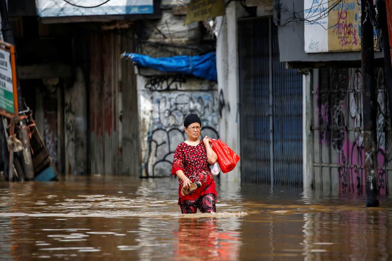 Woman carries her belongings across floodwaters in the Jatinegara area after heavy rains in Jakarta