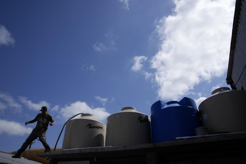 Jose Manuel Perez Reyes uncoils a hose as he delivers water to an auto mechanic shop from his water truck Tuesday, May 9, 2023, in Tijuana, Mexico. Among the last cities downstream to receive water from the shrinking Colorado River, Tijuana is staring down a water crisis. (AP Photo/Gregory Bull)