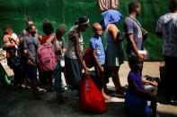 Migrants queue to get on buses after accepting an offer from the Mexican government to obtain humanitarian visas to transit the Mexican territory, at a stadium in Tapachula