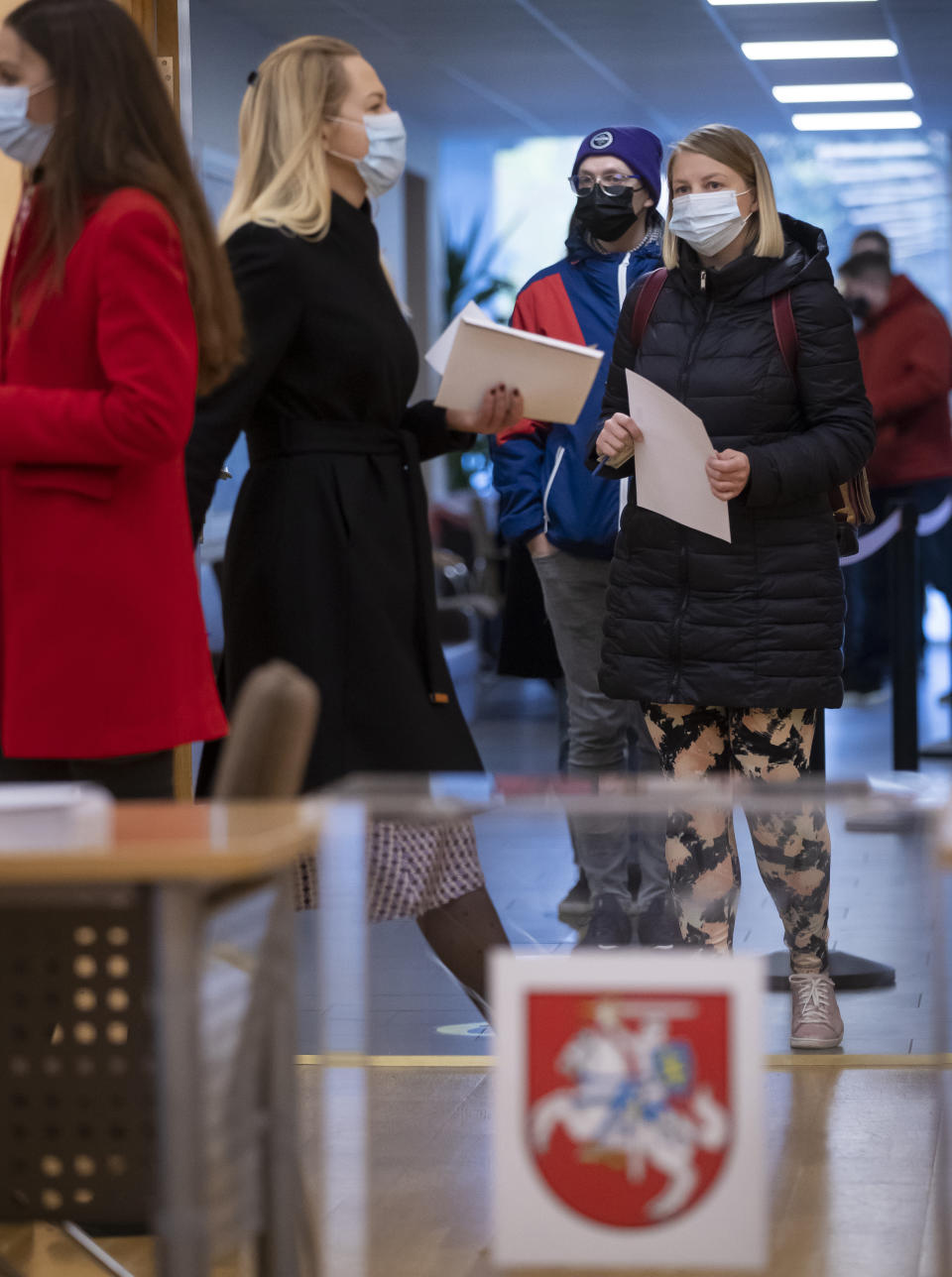 Lithuanian's, wearing face masks to protect against coronavirus, queue to cast their ballots at a polling station during early voting in the second round of a parliamentary election in Vilnius, Lithuania, Thursday, Oct. 22, 2020. Lithuanians will vote in the second round of a parliamentary election on upcoming Sunday during the rise in the incidence of coronavirus infection in the country. (AP Photo / Mindaugas Kulbis)