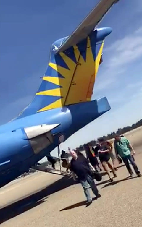 Passengers leave an Allegiant Air jet after it landed with smoke in the cabin at Fresno Yosemite International Airport - Credit: AP