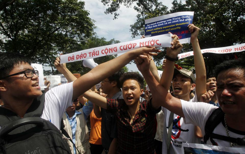 Protesters hold up banners which read, "Down with Chinese invaders" (white) while marching in an anti-China protest on a street in Hanoi May 11, 2014. Hundreds rallied on Sunday in Vietnam's biggest cities to denounce China's setting up of a giant oil rig in the South China Sea, a rare protest likely to prolong a tense standoff between the two communist neighbours. REUTERS/Kham (VIETNAM - Tags: POLITICS CIVIL UNREST)