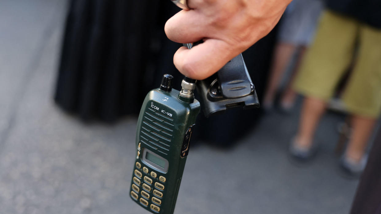 A man holds an Icom walkie talkie device after he removed the battery during the funeral of persons killed when hundreds of paging devices exploded in a deadly wave across Lebanon the previous day, in Beirut's southern suburbs on September 18, 2024. Hundreds of pagers used by Hezbollah members exploded across Lebanon on September 17, killing at least nine people and wounding around 2,800 in blasts the Iran-backed militant group blamed on Israel.