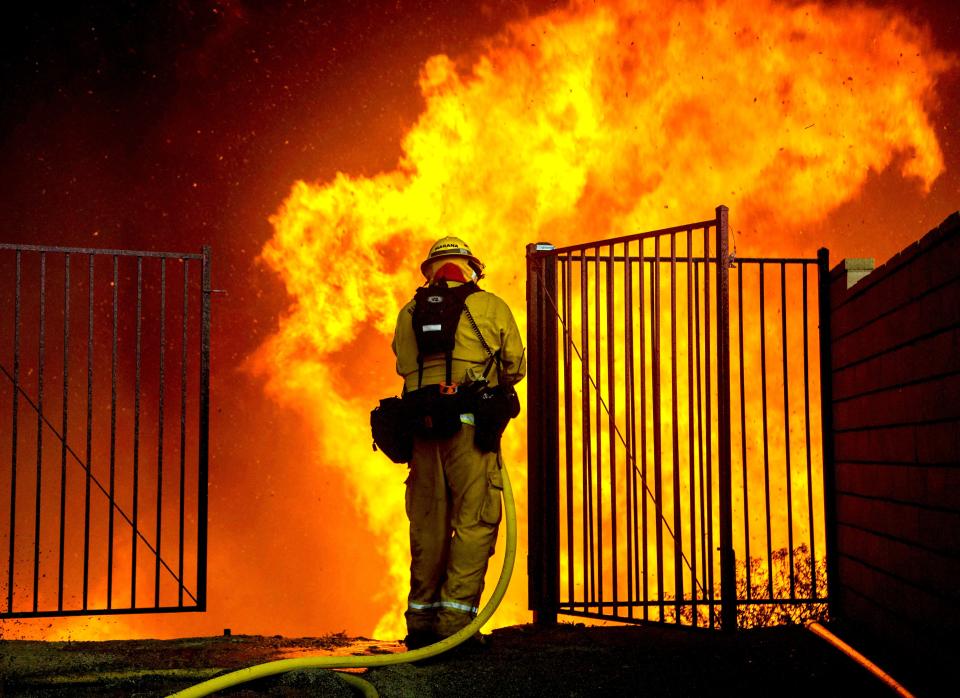 <p>A firefighter battles flames next to homes during the Holy Fire in Lake Elsinore, Calif., Aug. 9, 2018. (Photo: David McNew/EPA-EFE/REX/Shutterstock) </p>