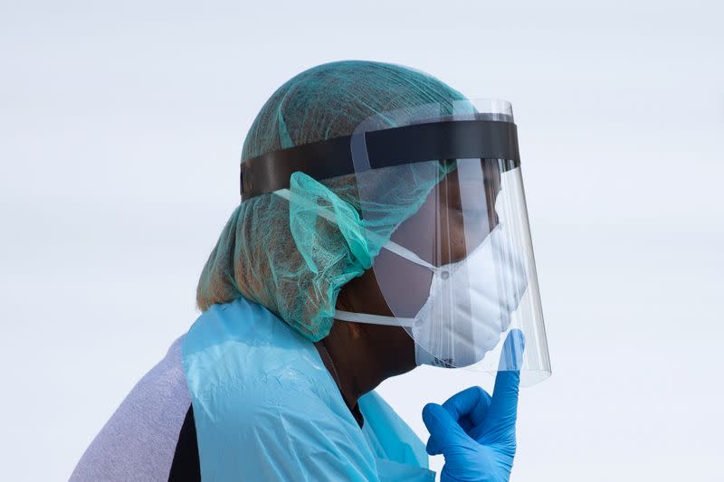 Healthcare worker points towards her mask at COVID-19 drive in testing location in Houston, Texas