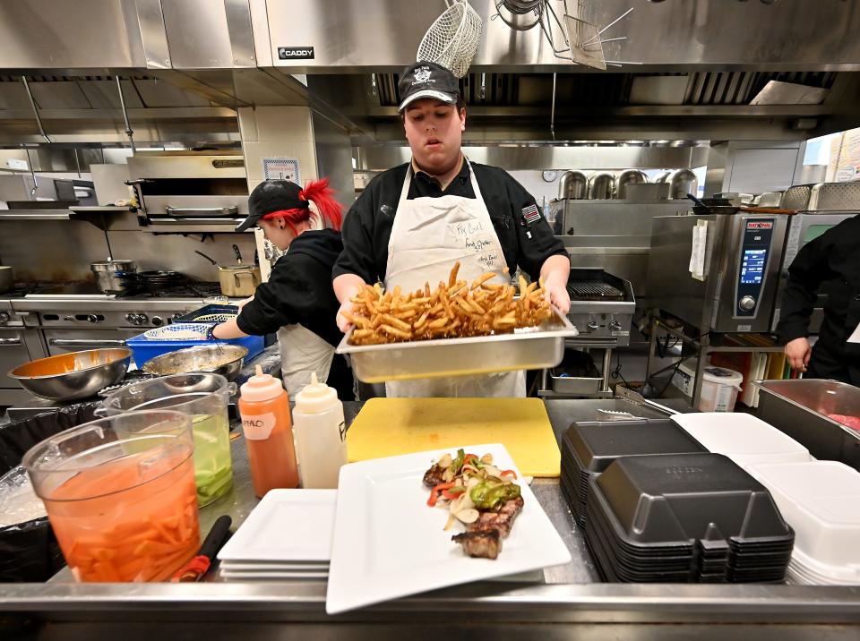 Bay Path Regional Vocational Technical High School culinary student and and junior Lexie Harris of Charlton tosses fries and seasoning in the kitchen.