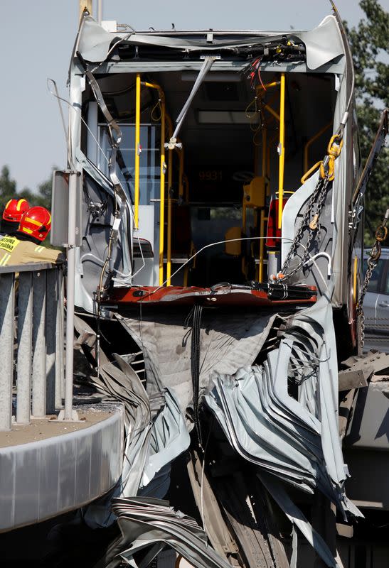 Emergency personnel work at the site of a crash after a city bus fell off a motorway bridge in Warsaw