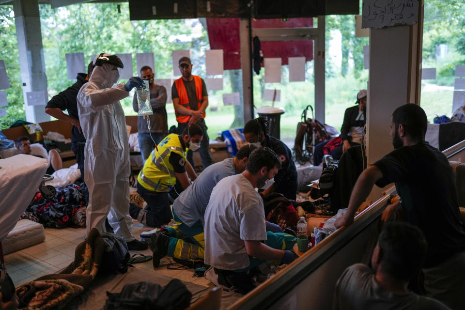 Red Cross health workers attend a man on hunger strike to be transferred to a hospital as he occupies with others a big room of the ULB Francophone university in Brussels, Tuesday, June 29, 2021. More than two hundreds of migrants without official papers and who have been occupying a church and two buildings of two Brussels universities since last February, began a hunger strike on 23 May to draw the attention of Brussels authorities to their plight. (AP Photo/Francisco Seco)