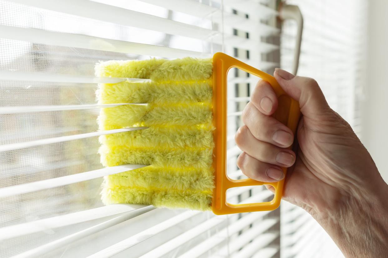 Woman cleans blinds with a rag indoors, close-up,