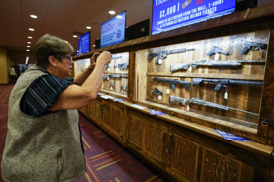 Trudy Jackson takes a photo of a display of guns in the Indiana Convention Center, Thursday, April 13, 2023, in Indianapolis. The NRA Convention starts Friday, April 14 and end on Sunday, April 16. (AP Photo/Darron Cummings)