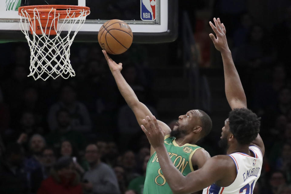 Boston Celtics guard Kemba Walker (8) scores against Philadelphia 76ers center Joel Embiid in the first quarter of an NBA basketball game, Thursday, Dec. 12, 2019, in Boston. (AP Photo/Elise Amendola)