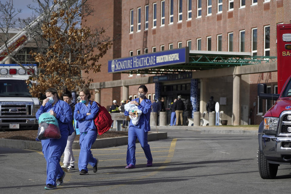 Medical staff walk away from an entrance to Signature Healthcare Brockton Hospital, Tuesday, Feb. 7, 2023, in Brockton, Mass. A fire at the hospital's electrical transformer forced an undetermined number of evacuations Tuesday morning and power was shut off to the building for safety reasons, officials said. (AP Photo/Steven Senne)