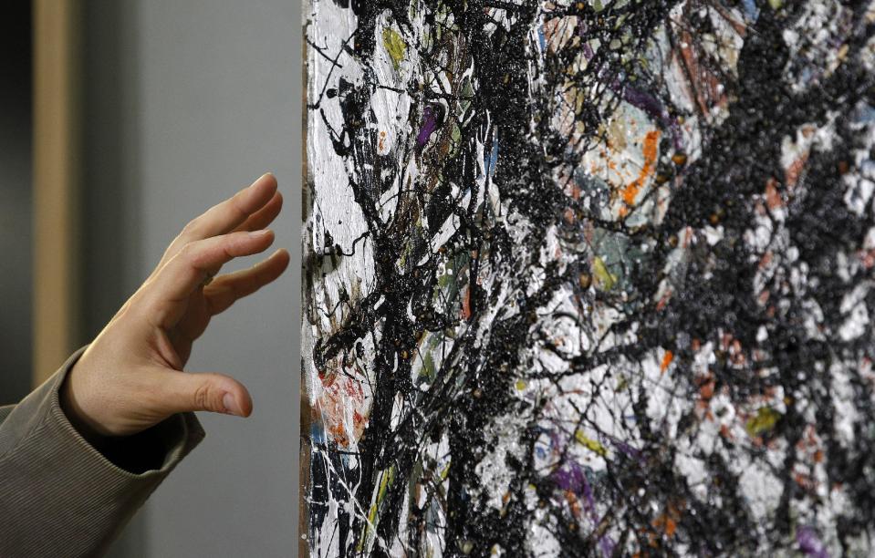 Nicholas Dorman, chief conservator for the Seattle Art Museum, points to the canvas as he talks about his on-going restoration work of Jackson Pollock's painting Sea Change during a news conference Tuesday, Nov. 27, 2012, at the museum in Seattle. The celebrated piece, part of SAM's permanent collection, was painted in 1947 and altered in 1970 with a coat of varnish. Dorman is several months into the restoration work, which is complicated by the uneven surface and multiple layers of media, including several types of paint and imbedded gravel. The restoration is sponsored by Bank of America's Art Conservation Project, which enabled SAM staff and consulting experts to undertake a study of the original materials and evaluate the impact of materials used in conservation treatments. (AP Photo/Elaine Thompson)