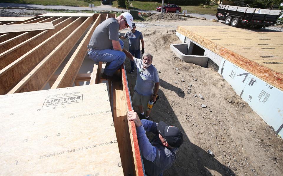 Chuck Abbott (center) gets help from volunteers from First Interstate Bank, including John Kemmett, Justin Witek, and David Tucker. The quartet are helping build a trio of Habitat for Humanity homes along Wilmoth Street.