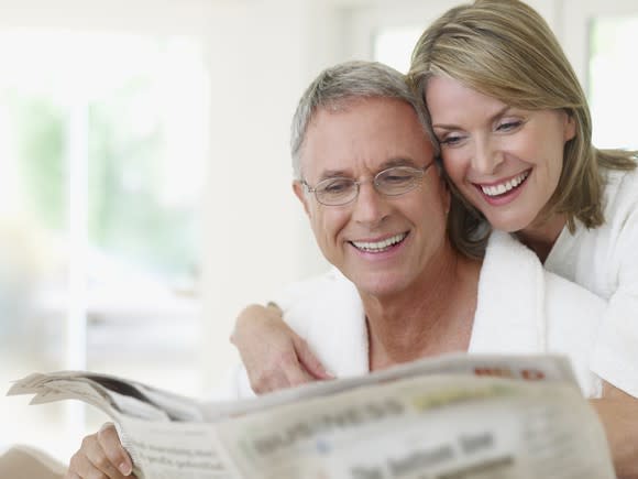 Smiling older couple reading a newspaper