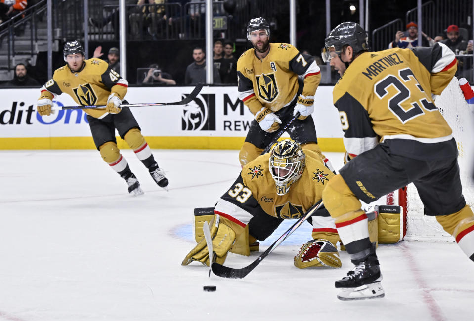Vegas Golden Knights goaltender Adin Hill (33) dives for the puck with help from defenseman Alec Martinez (23) during the third period of the team's NHL hockey game against the Edmonton Oilers on Tuesday, Feb. 6, 2024, in Las Vegas. (AP Photo/David Becker)