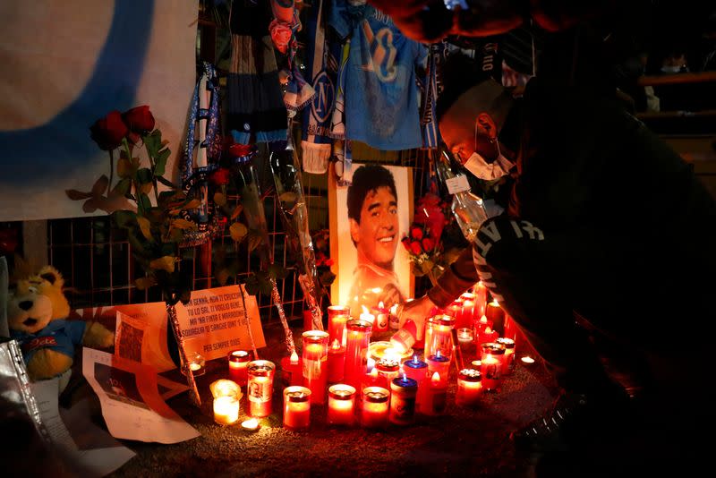 Un hombre enciende una vela en homenaje a la leyenda del fútbol argentino Diego Maradona fuera del Stadio San Paolo en Nápoles, Italia